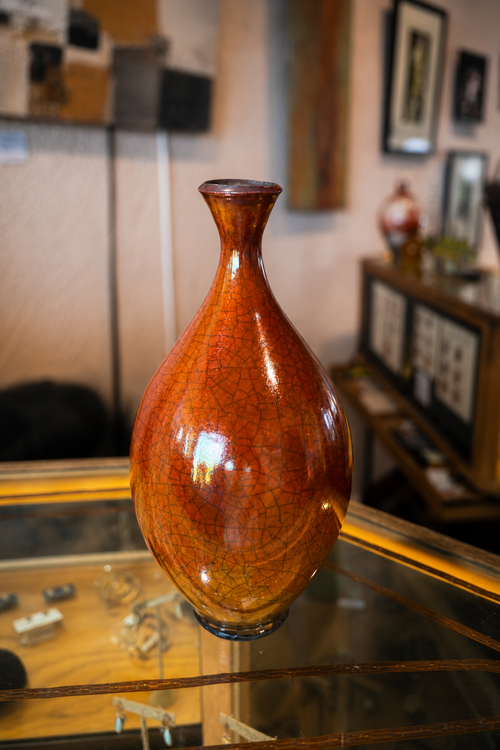 Orange Raku ceramic vase with a long neck and natural crackled surface