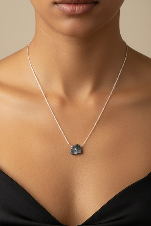 Woman wearing an oxidized sterling silver petal pendant necklace with cubic zirconia, modern handcrafted jewelry for everyday elegance and special occasions.