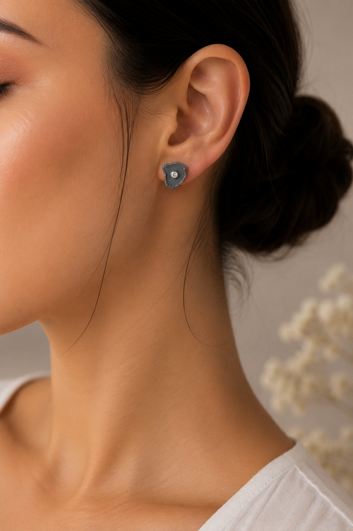Woman wearing handcrafted oxidized sterling silver petal stud earrings with cubic zirconia, modern minimalist designer jewelry and an elegant gift for her.