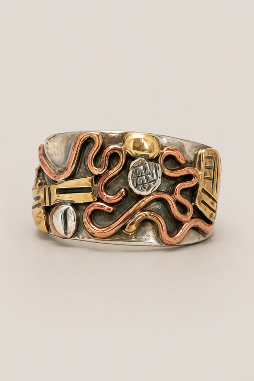 Close-up of handmade sterling silver, copper and brass wide band ring with raised mixed metal design