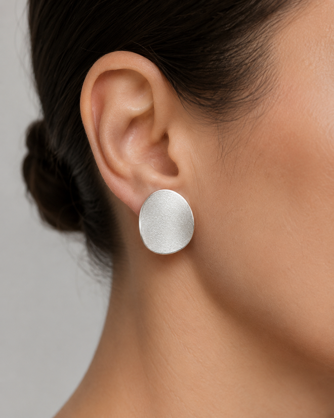 Sterling silver curved disc stud earrings shown on ear