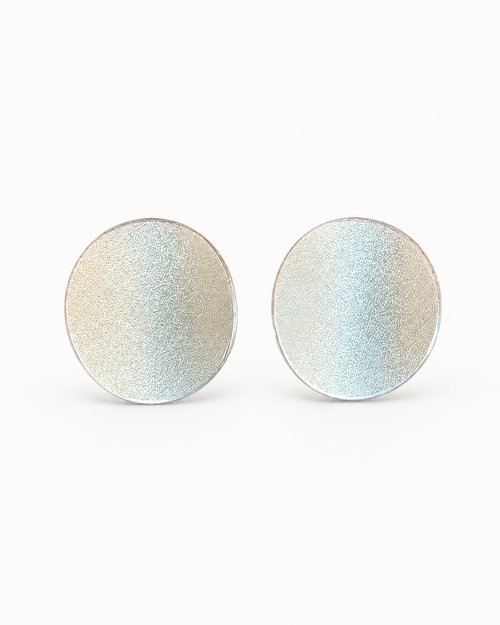 Sterling silver curved disc stud earrings displayed on marble in a luxury setting