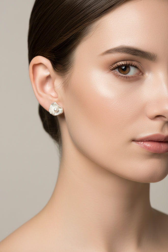 Woman wearing handmade sterling silver petal stud earrings featuring genuine freshwater pearls, contemporary artisan floral jewelry with an elegant organic design for everyday wear and special occasions.
