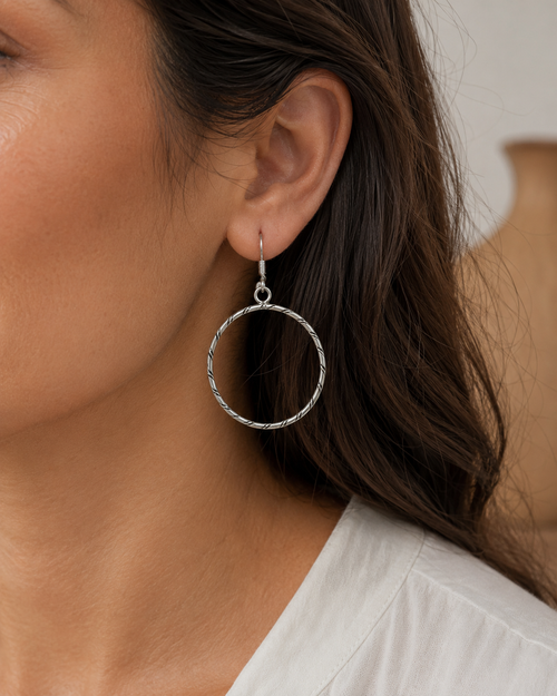 Sterling silver round hoop earrings shown on ear, handmade Southwestern jewelry by Navajo artist Caroline Tsosie.