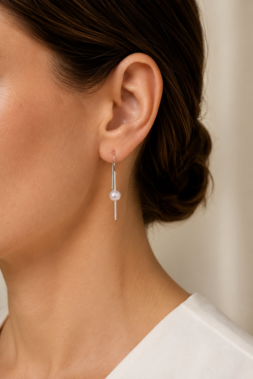 Sterling silver freshwater pearl drop earrings shown on ear for size and fit
