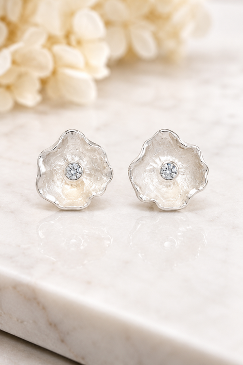 Close-up of a model wearing handcrafted sterling silver petal stud earrings with sparkling cubic zirconia in a timeless floral design.