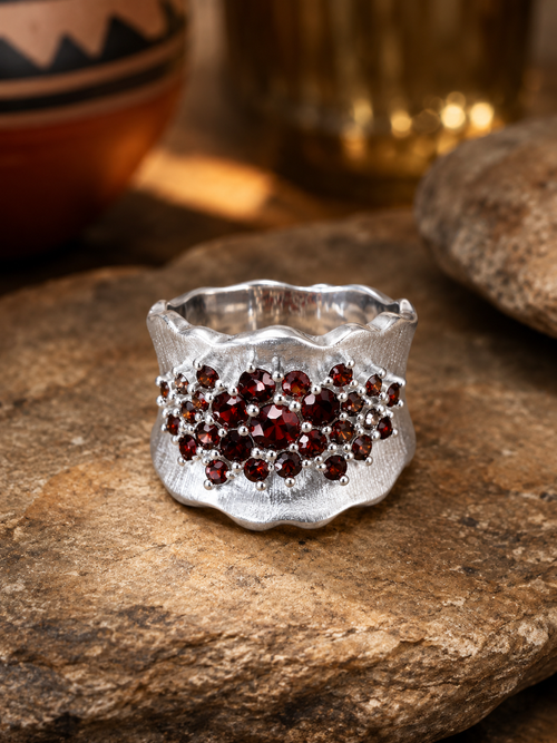 Close-up of a handcrafted sterling silver designer ring with a multi-cluster of natural garnets, highlighting the rich gemstone color and satin silver finish.