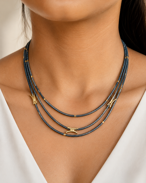 Three-strand hematite necklace with charcoal gray beads and gold accents on white background