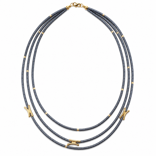 Woman wearing a three-strand hematite beaded necklace with gold accents and layered contemporary design