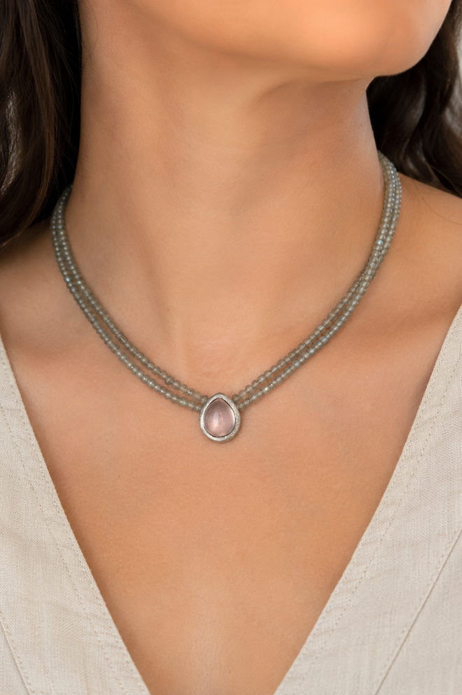 Woman wearing a handmade two strand Labradorite necklace with a 9x12mm pear-shaped Rose Quartz pendant in a matte dark sterling silver setting.