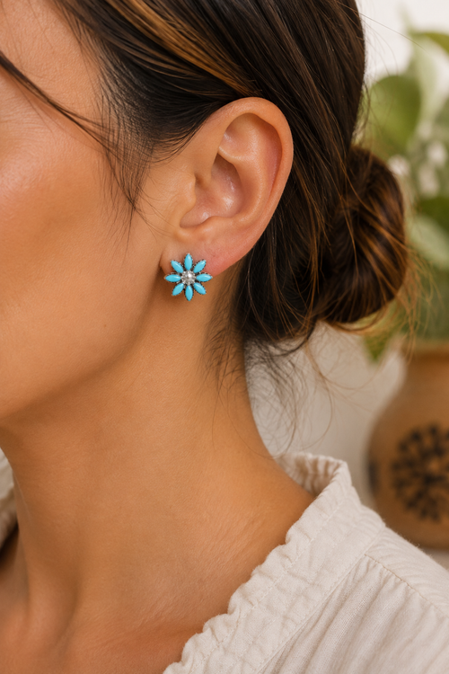 Zuni Kingman turquoise sterling silver flower stud earrings shown on ear, approximately 5/8 inch diameter